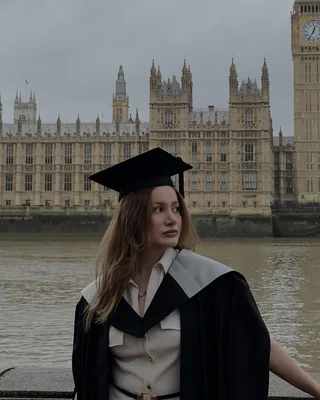 Elmira in a graduation gown by the Thames, with Big Ben behind her