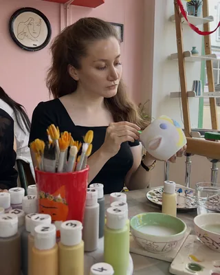 Elmira painting a ceramic piece at a pottery studio