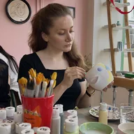 Elmira painting a ceramic piece at a pottery studio